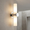 Modern chrome bathroom wall light with twin vertical frosted glass shades mounted on a tiled wall.
