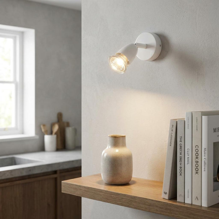Saxby Amalfi gloss white finish single spotlight illuminating a ceramic vase on a wooden shelf.