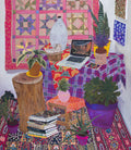 The vibrant indoor scene showcases plants, a laptop, and books. A colorful quilt is displayed on the wall above Anna Valdezs archival pigment print titled References. A wooden stool supports a potted plant, with patterned fabrics covering the floor and table. This limited edition piece is signed and numbered for collectors.