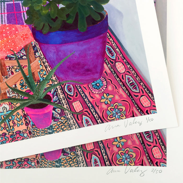 The References limited edition archival pigment print by Anna Valdez features colorful succulents in purple pots on a vibrant patterned rug. Each signed artwork, labeled with edition numbers 1/50 and 2/50, showcases intricate designs.