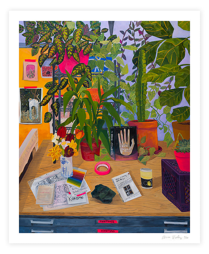 The Anna Valdez - Ways of Seeing print, a limited edition archival pigment print, portrays a vibrant still life of a desk with colorful plants, books, trinkets, and scattered art supplies. Each piece is signed and numbered by artist Anna Valdez.