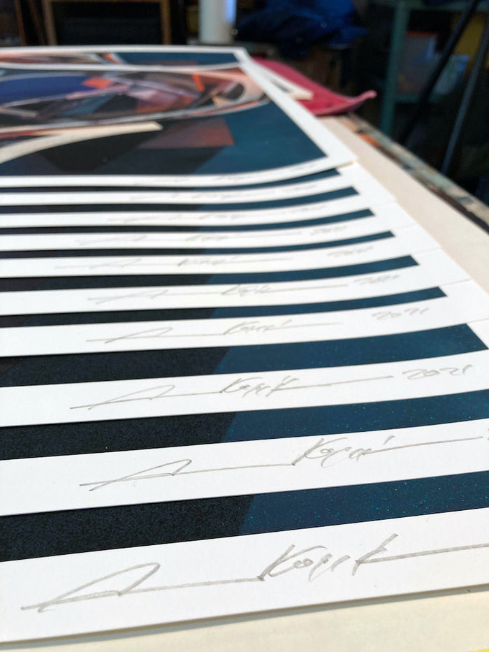 A close-up of several "Dodge&Move" archival pigment prints by Augustine Kofie laid out in a row, each featuring the artist’s signature and the year 2021 written in pencil on the white border at the bottom of these signed and numbered limited editions.