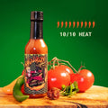 Bad Boy Cobra Venom hot sauce bottle with black cap, surrounded by fresh peppers and tomatoes on wooden surface