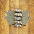 Gray heat-resistant grill gloves with five sausages on wooden surface
