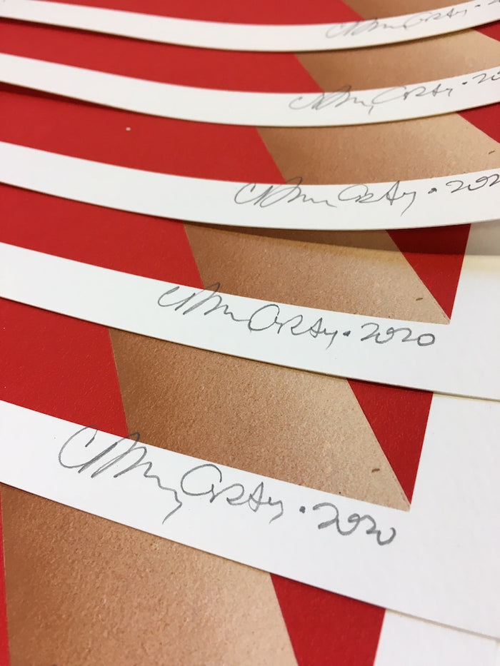 Close-up of several white paper strips featuring handwritten signatures and the year 2020 in pencil, arranged on a red and light brown striped surface. "Cheers" by Casey Gray is an archival pigment print, offered as a signed and numbered limited edition by the artist.