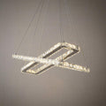 Intersecting chrome and crystal rectangular LED ceiling pendant hanging against a textured neutral wall.