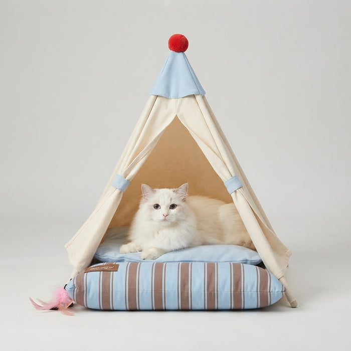 White cat lying on the cushioned floor of a beige indoor pet teepee