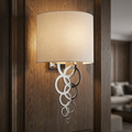 Polished chrome wall light with a cream shade and interlocking rings, mounted on a dark wood-paneled wall.