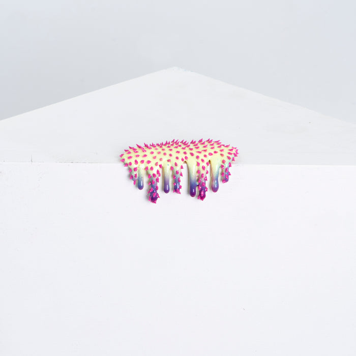 Mini #15 by Dan Lam is a small, colorful art piece with prickly textures in vibrant pinks and purples on a stark white angular surface. Crafted from acrylic and hot glue, it creates a striking contrast.