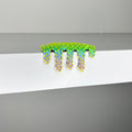 Dan Lam's "Mini #268" is a small, green and blue spiky art object with yellow dots that seems to melt or drip over the edge of a white shelf against a gray background, showcasing the artist’s playful use of mixed media in this 2023 creation.