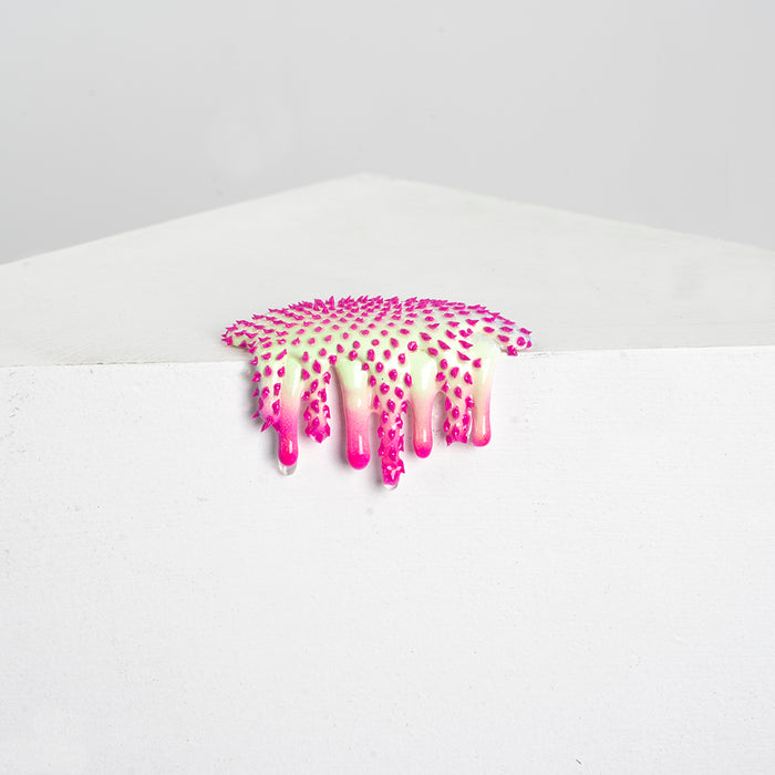 The Dan Lam Mini #29 by the brand Dan Lam is a clear plastic patch that looks like resin, featuring pink/white dots and drips, decoratively hanging over a white surface corner against a plain grey background.