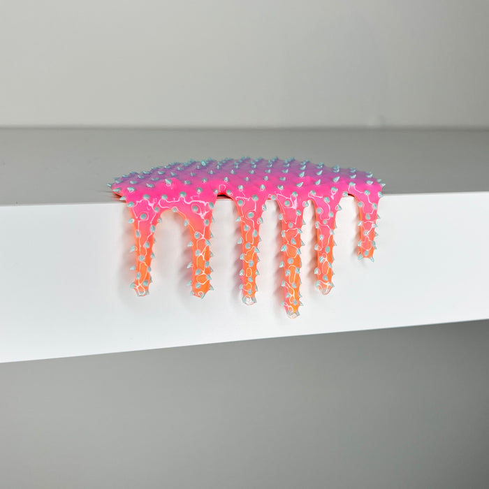 Dan Lams Mini #407 is a pink and orange mixed media piece (2 x 3 3/4 x 2 inches) with a textured, studded pattern and glossy finish, evoking melted paint drips over a white shelf for a striking visual effect against its minimalist background.