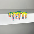 Dan Lams Mini #510 features a spiky, neon yellow and orange design with blue tips dripping over a white shelf against a plain backdrop. Reminiscent of 2023 mixed media art, its colorful and abstract style blends liquid and spiked textures.