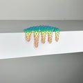 Dan Lam’s "Mini #570" is a colorful, spiky, blob-like mixed media sculpture featuring dramatic drips that spill over the edge of a white surface against a plain gray background.