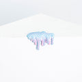 Mini #6 by Dan Lam, a surreal resin blob with blue spikes and pink drips, sits whimsically on a white surface amidst a minimalist white background.
