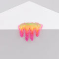 The vibrant Dan Lam Mini #7.07 from Dan Lam features an iridescent slime blob in shades of yellow, orange, and pink that drips over a white triangular surface like melting candy, resembling glossy resin.