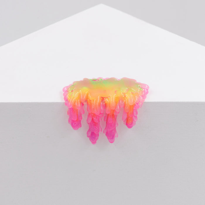 The vibrant Dan Lam Mini #7.07 from Dan Lam features an iridescent slime blob in shades of yellow, orange, and pink that drips over a white triangular surface like melting candy, resembling glossy resin.