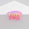 Iridescent, glossy pink, yellow, and purple resin slime from Dan Lam’s "Mini #7.08" drips over the edge of a white geometric surface against a plain light background.
