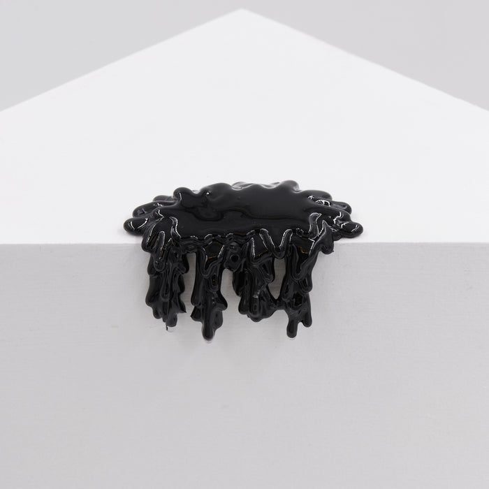 A glossy black liquid drips over a white geometric structure, resembling resin, with an organic flow. This striking effect in the artwork Mini #7.67 by Dan Lam combines acrylic art and natural forms against a plain backdrop.