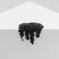 Dan Lams Mini #7.88 features acrylic black paint dripping down a white triangular surface, forming an abstract and glossy pattern against a light gray background.