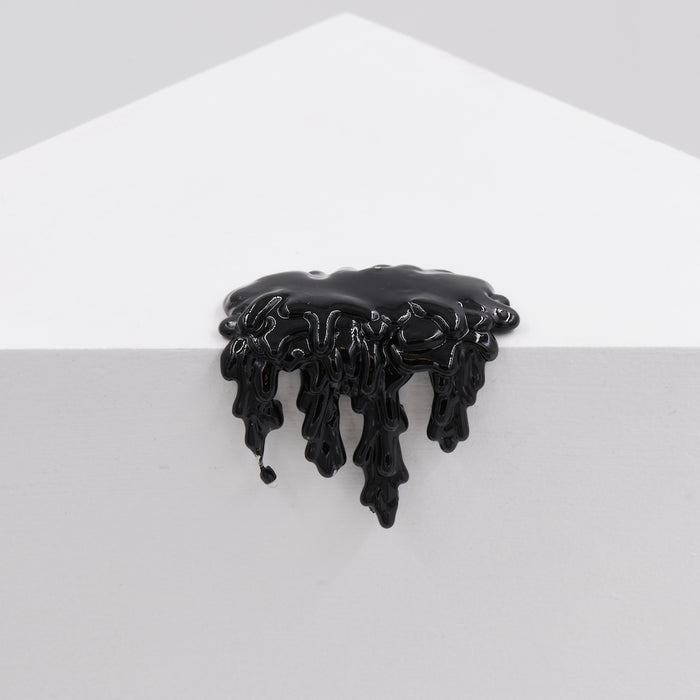 Dan Lams Mini #7.88 features acrylic black paint dripping down a white triangular surface, forming an abstract and glossy pattern against a light gray background.