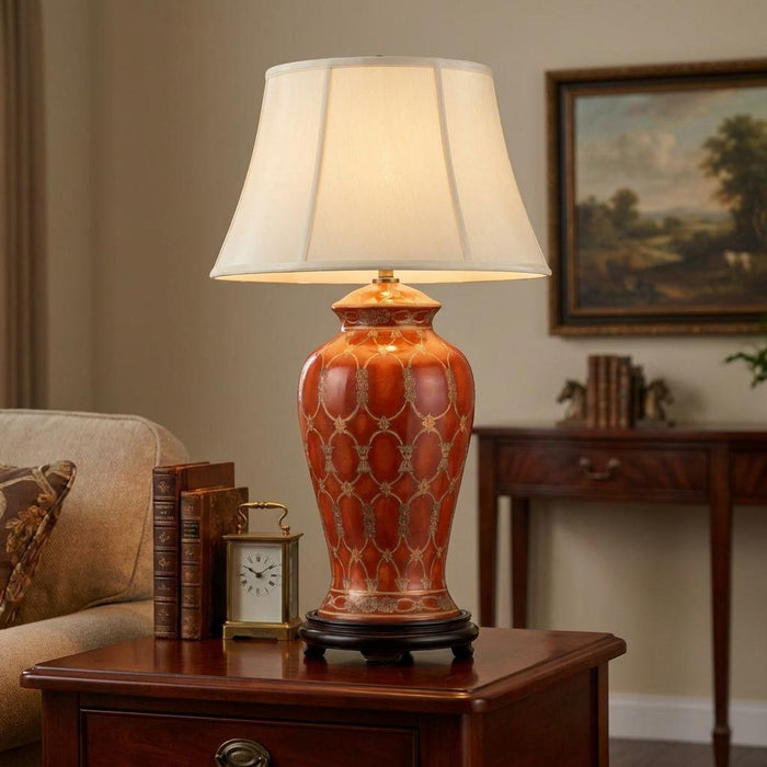 Terracotta ceramic table lamp with a white lattice pattern and cream shade on a wooden side table in a living room.