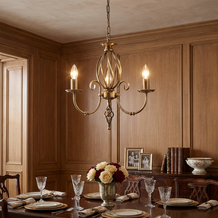 Elstead Artisan aged brass 3-light chandelier hanging over a formal dining table in a wood-paneled room.