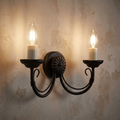 Elstead Chartwell black two-light wall sconce with candle bulbs mounted on a rustic textured wall.