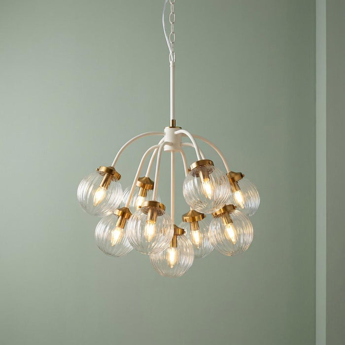 Elstead Cosmos nine-light brass and cream ceiling pendant with ribbed glass globes on a light green background.