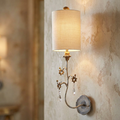 Flambeau Tivoli wall light with silver ornate arm, crystal drops, and cream fabric shade on a textured wall.