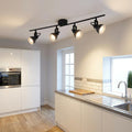 Four black adjustable spotlights on a ceiling bar illuminate a modern white kitchen.