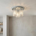 Glamour Chrome 3 light semi-flush ceiling light with crystal shades casting a glow against a textured wall.