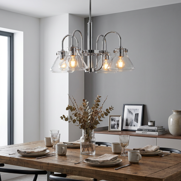 Chrome four-light chandelier with clear glass funnel shades illuminated above a wooden dining table in a modern home.