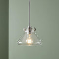 Hinkley Congress chrome pendant light featuring a clear glass tapered shade and glowing bulb against a green wall.