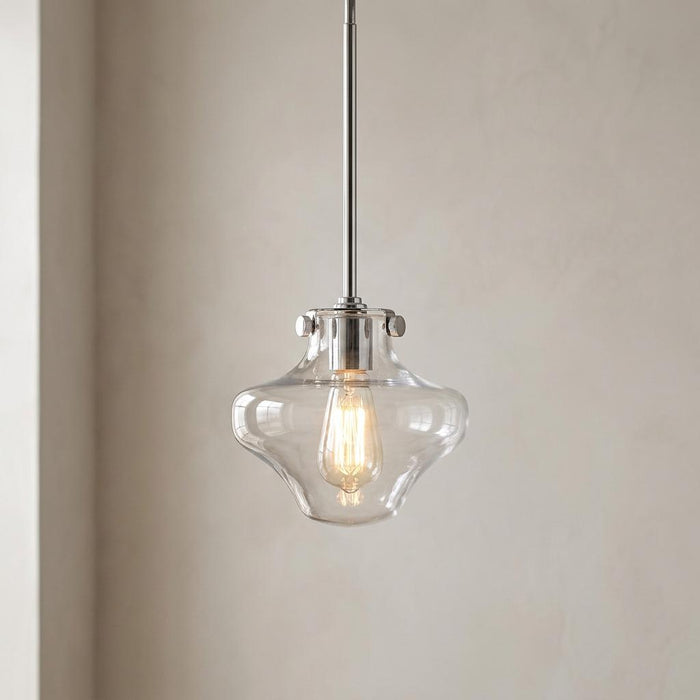 Chrome pendant light with a clear, shapely glass shade and glowing Edison bulb.