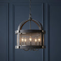 Hinkley Holden 5-light aged zinc chandelier with a mesh screen shade hanging against a dark blue paneled wall.
