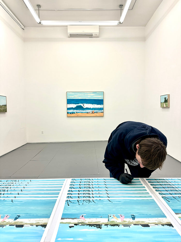 man signing Jean Jullien print of group of people windsurfing