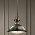 Kichler Hatteras Bay 33cm bronze pendant light with a domed shade and fresnel lens hanging in a room.