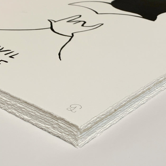 A close-up of the Devil Inside limited edition art print by Petites Luxures highlights its thick, textured paper with deckle edges. The minimalist black illustration, partially visible, features a signed and numbered mark near the edge, resting elegantly against a plain background.