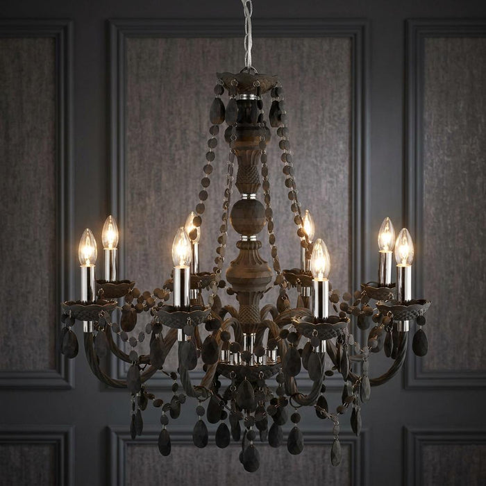 Searchlight Marie Therese 8 Light Grey Acrylic Chandelier with lit bulbs against a grey panelled wall.